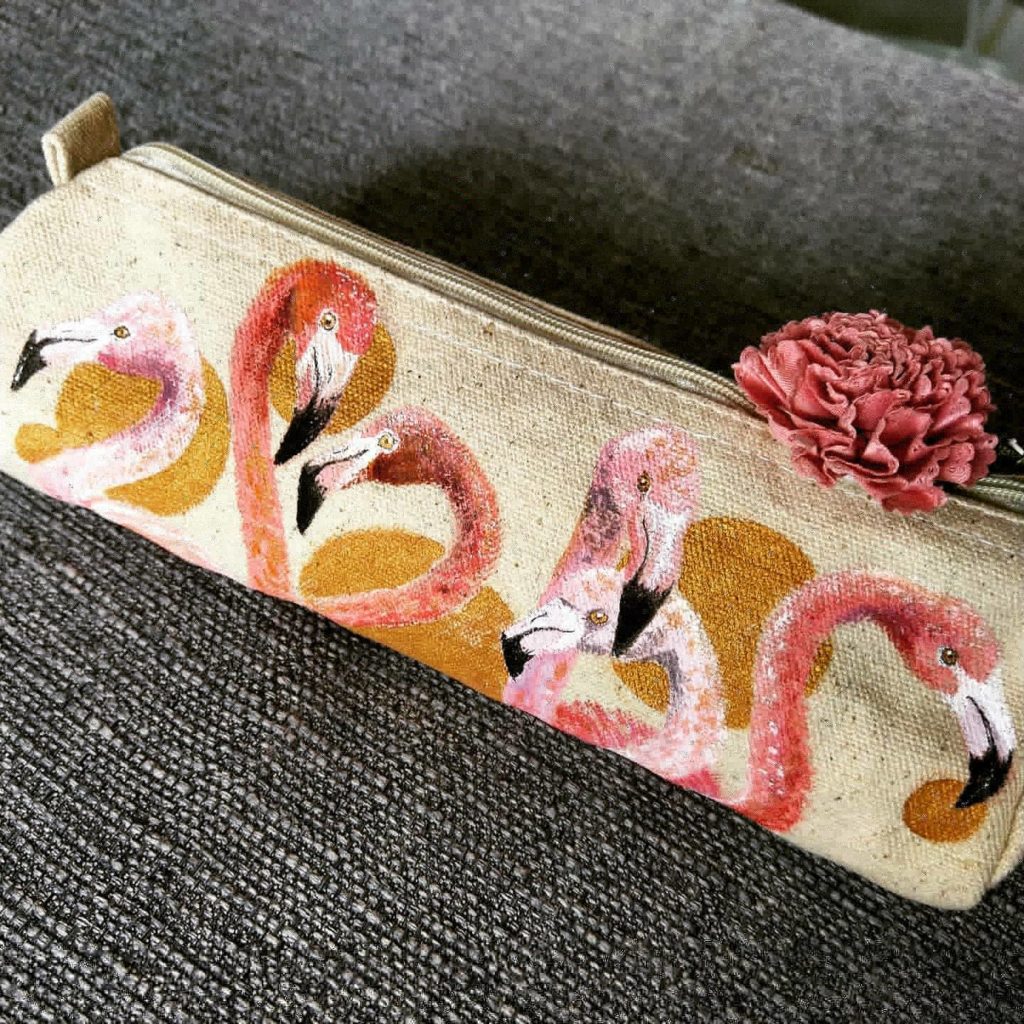mit Acrylfarbe gemalte Flamingos auf einer Stofftasche mit Reisverschluss